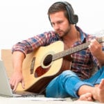 Man Playing Guitar Wearing Earphones | 3 Simple Steps to Teach Yourself Guitar Chords Today